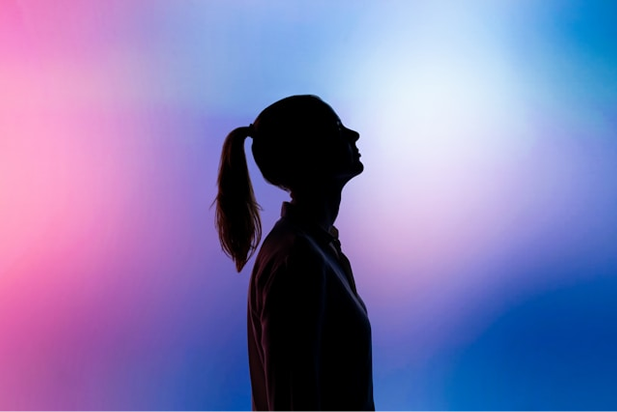 A silhouette of a person against a blue and pink background.